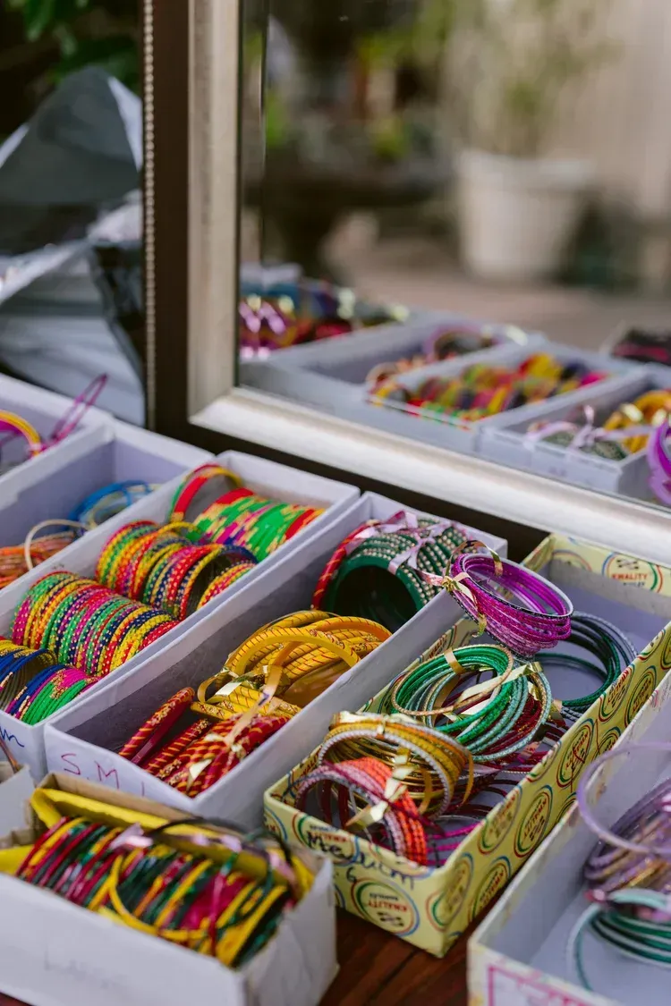 Colorful bracelets and bangles displayed in open boxes on a mirrored tabletop