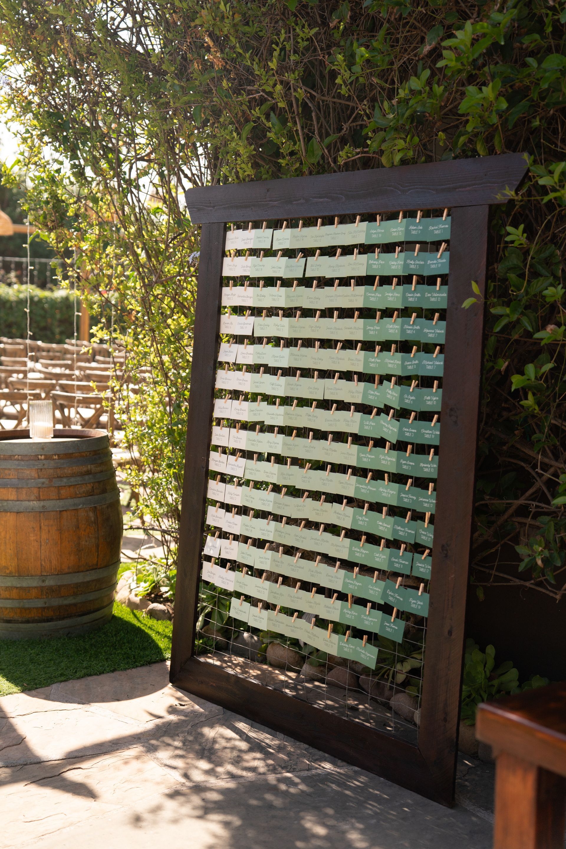 Wooden garden privacy screen with slatted green panels beside a path and barrel planter