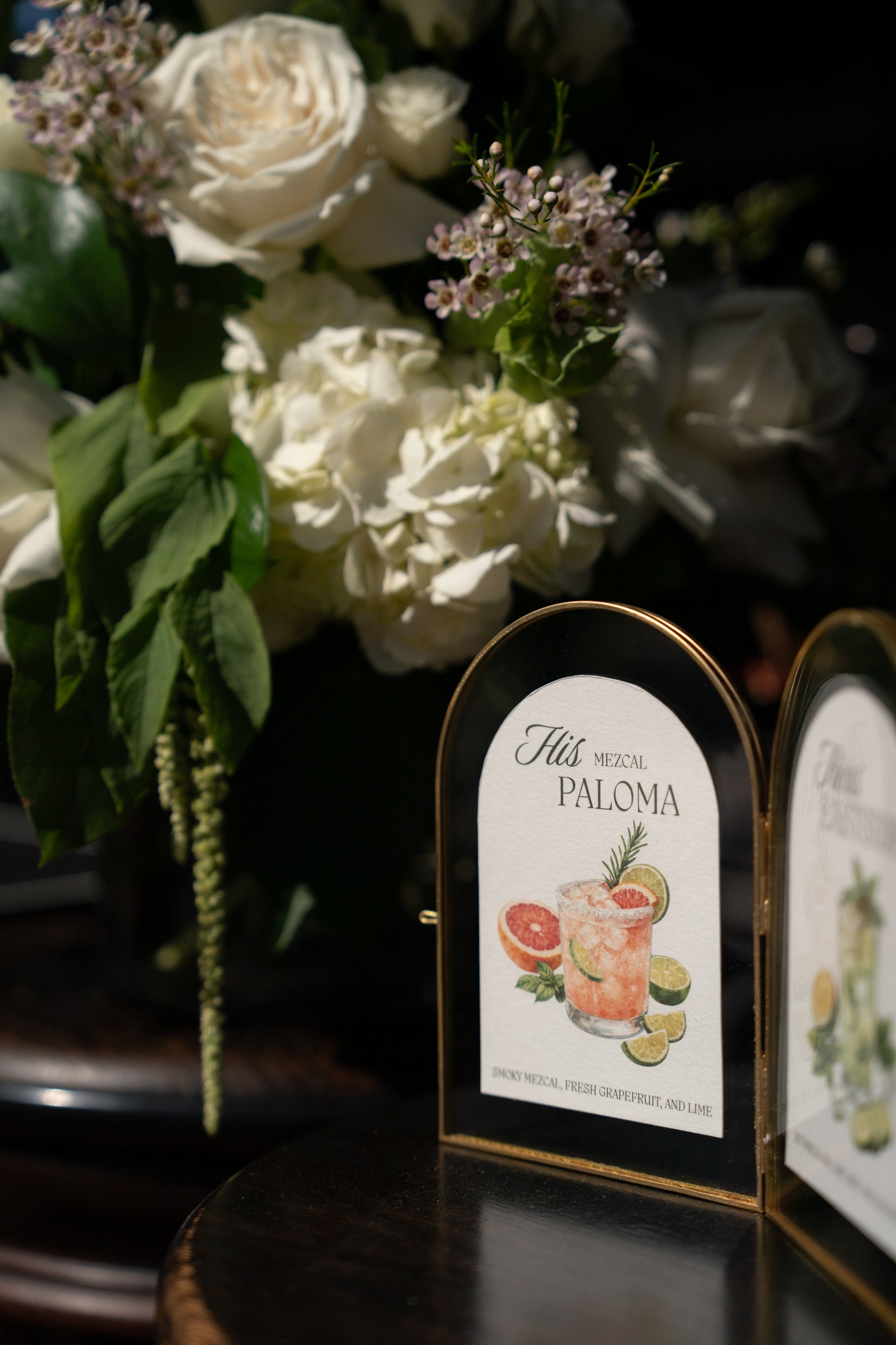 Floral arrangement beside two decorative table cards on a dark table, one reading “Bon Palm”