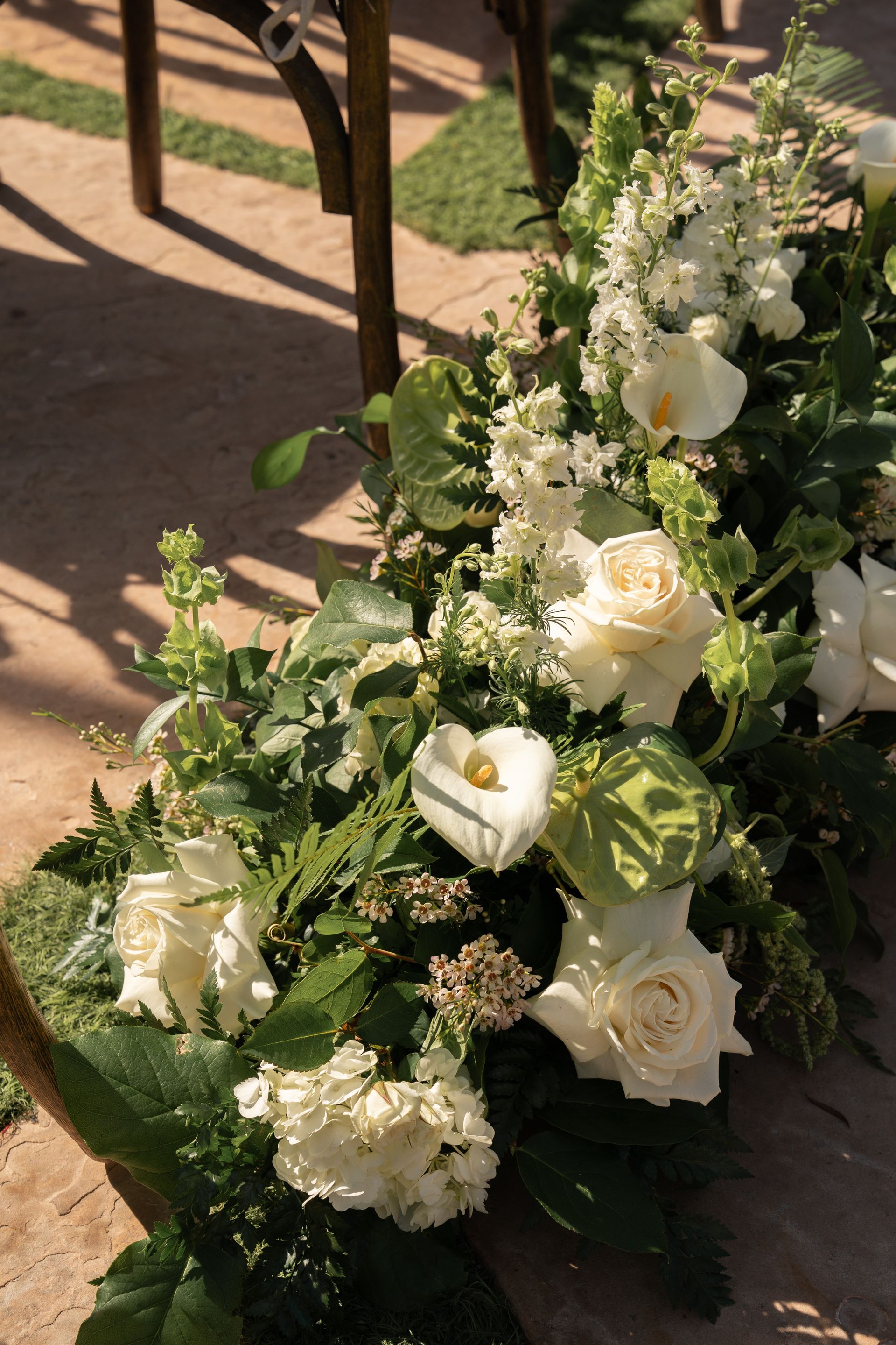 White floral arrangement with roses and greenery on a sunlit floor