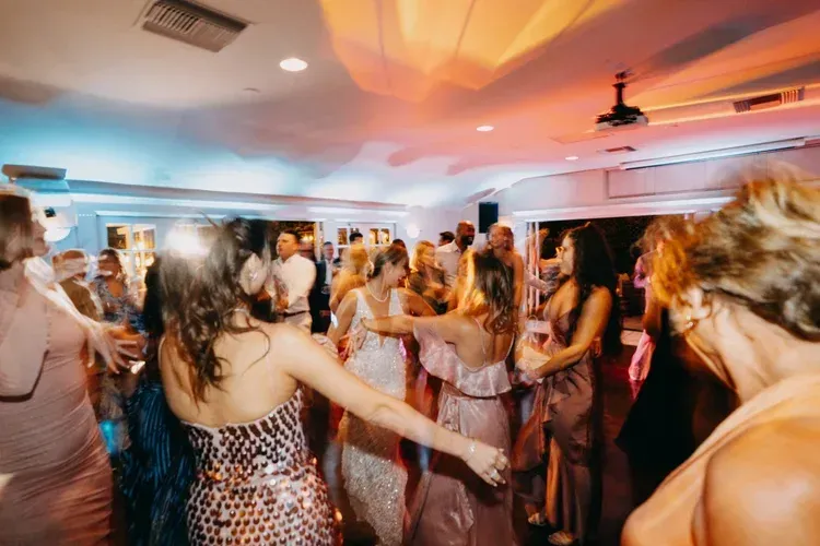People dancing in a warmly lit party room with colorful ceiling lights