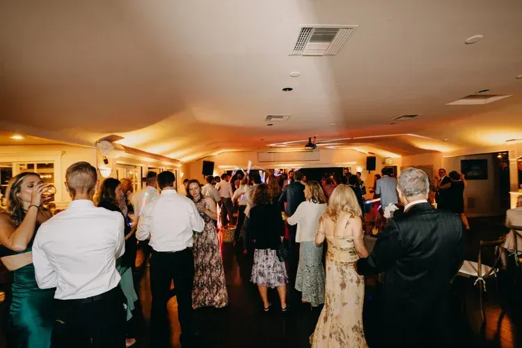 Guests socializing and dancing at a warmly lit indoor reception hall