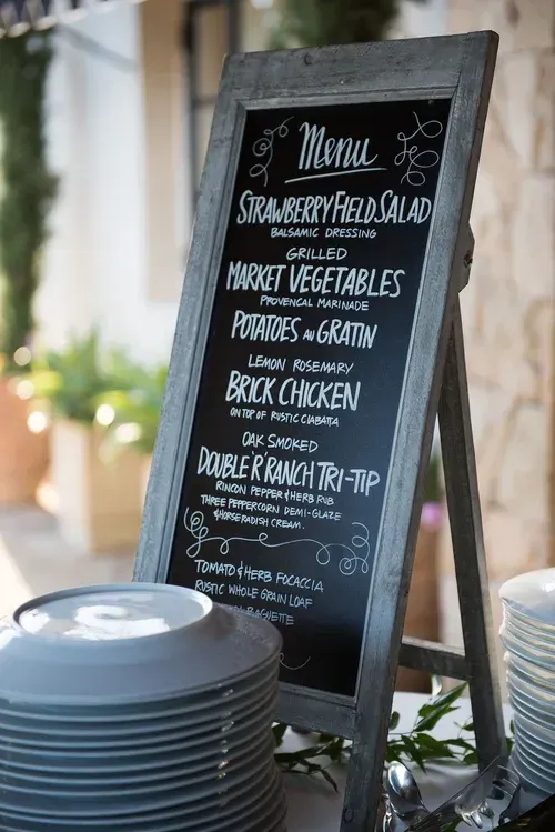 Chalkboard menu on an easel beside stacked plates in a rustic restaurant setting