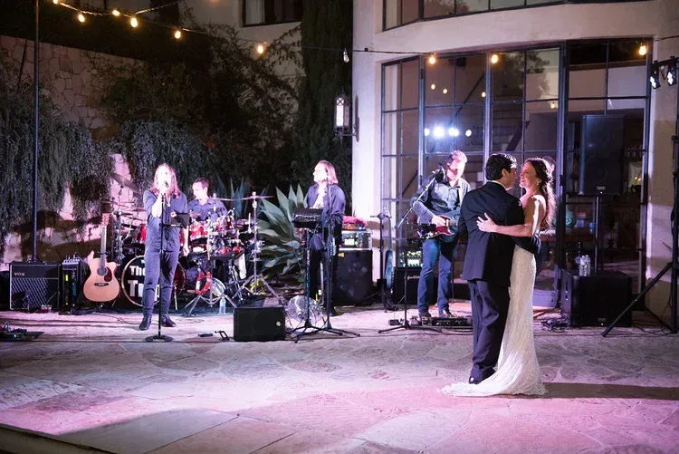 Wedding couple dancing while live band performs outdoors at night