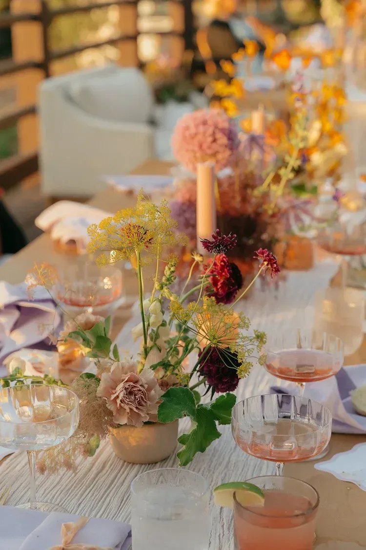 Elegant banquet table with floral centerpieces, candles, and glassware in warm evening light