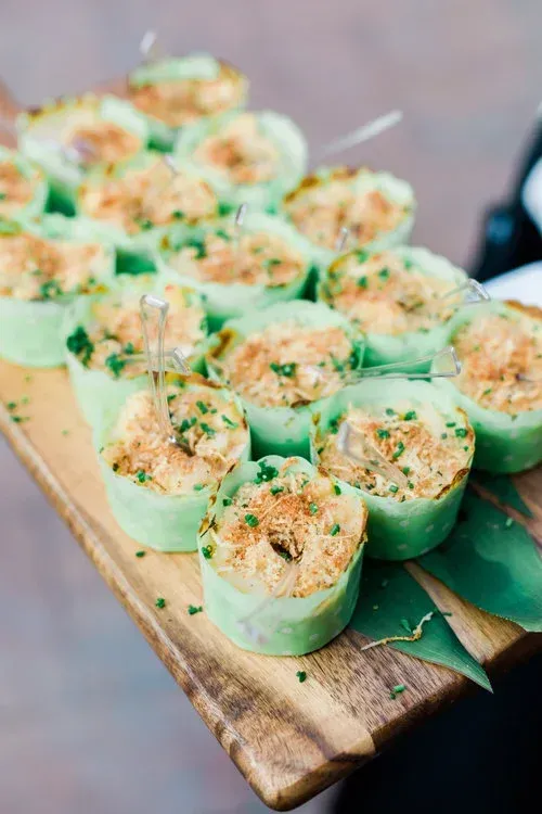 Platter of cucumber cups topped with a creamy herb filling on a wooden board