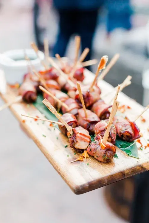 Skewered grilled meat on a wooden board, garnished with herbs and sauce