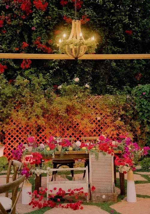 Flower-filled garden patio with a chandelier, lattice backdrop, and a set dining table