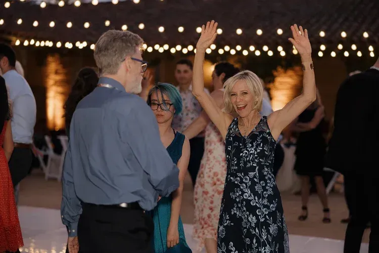 People dancing at an evening party under string lights
