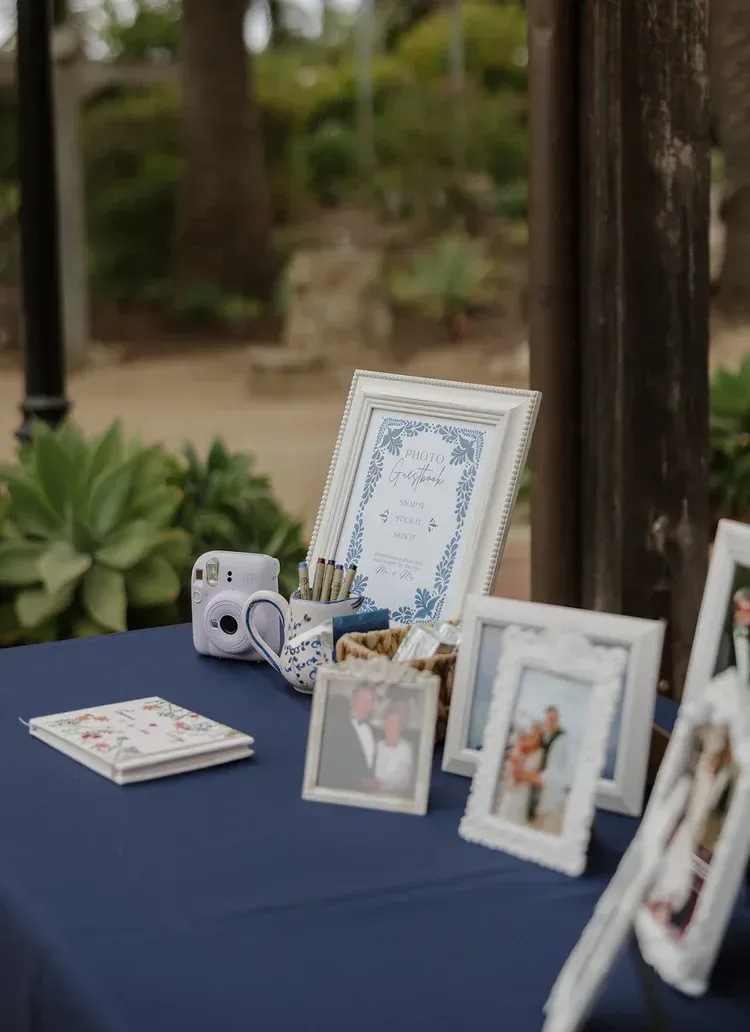 Blue table with framed photos, a small camera, and a decorative sign at an outdoor event