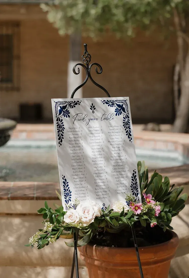 Decorative white memorial sign with floral arrangement in a terracotta pot outdoors