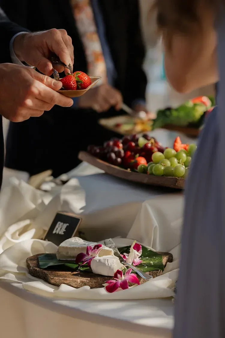 Hands serving colorful appetizers at a catered buffet table