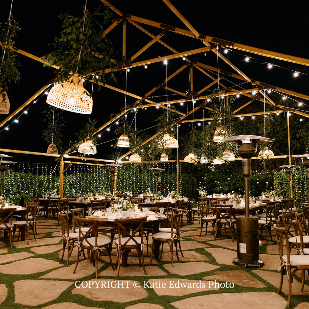 Outdoor dining area under string lights with wooden tables and chairs at night