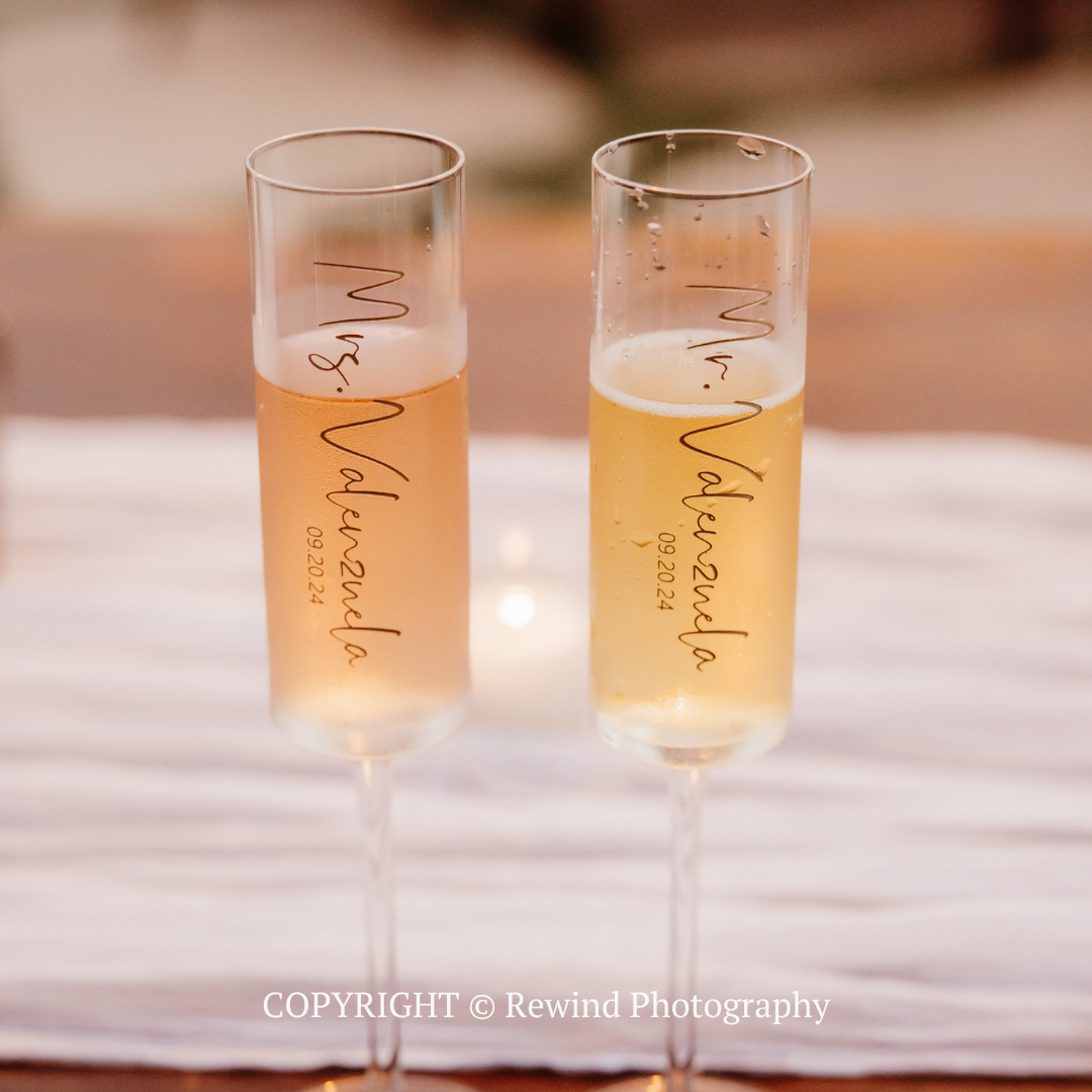 Two champagne flutes with pale orange drinks, set on a softly blurred table.