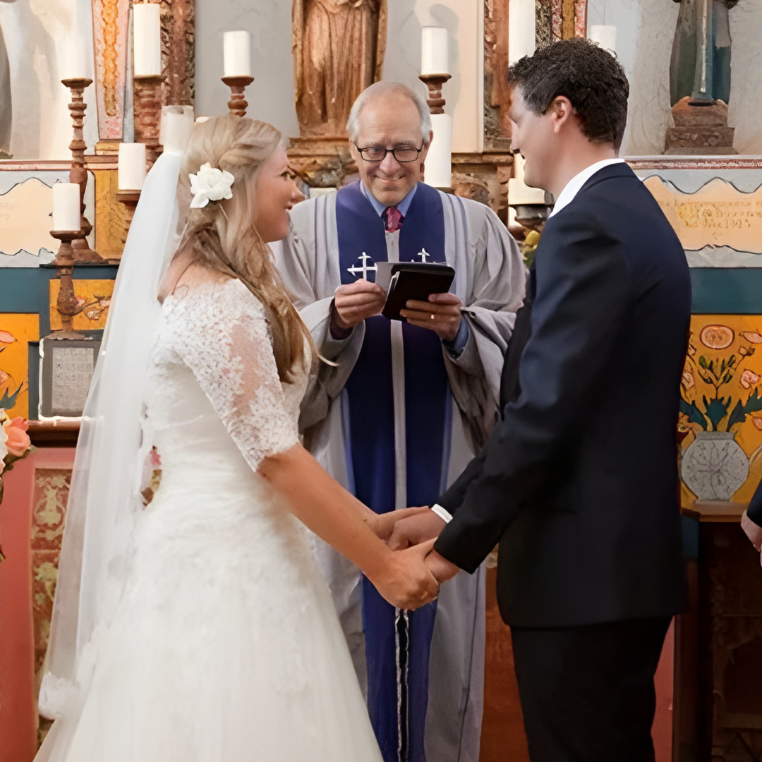 Bride and groom hold hands during a church wedding ceremony as the officiant speaks.