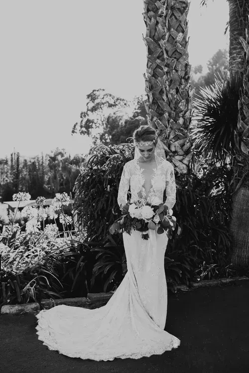 Bride in a long white gown holding a bouquet in a garden setting