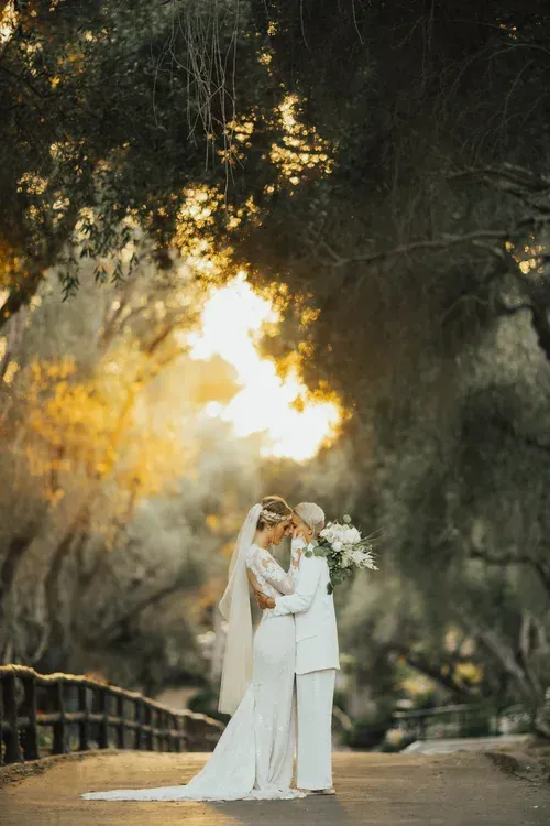 Bride and groom embracing on a tree-lined path at sunset