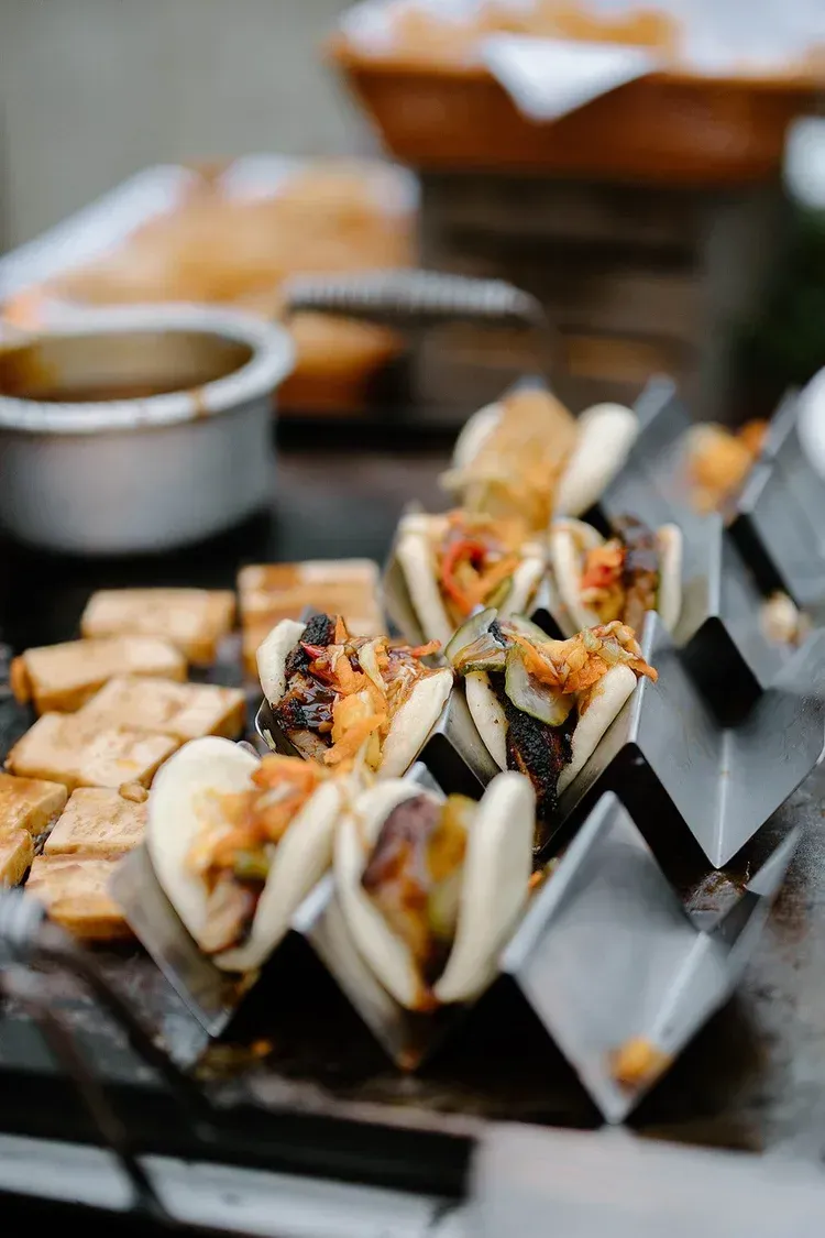 Grilled skewered seafood and vegetables on a tabletop grill, with dipping sauce nearby