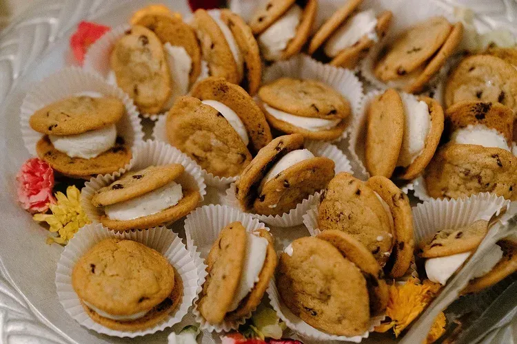Assorted pastries and cookies arranged in white paper cups on a tray