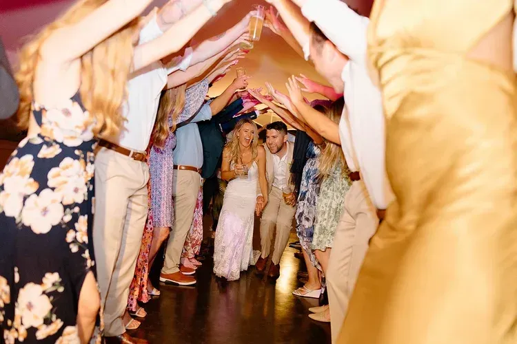 People dancing in a colorful tunnel of raised arms at a lively party or celebration