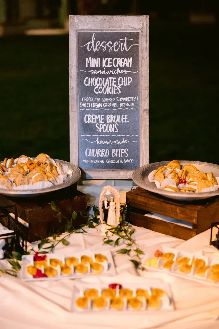 Dessert buffet with a chalkboard menu and plated pastries on a warmly lit table