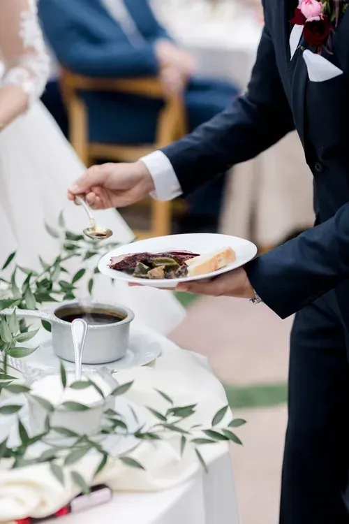 Server carrying plated food at a wedding reception table
