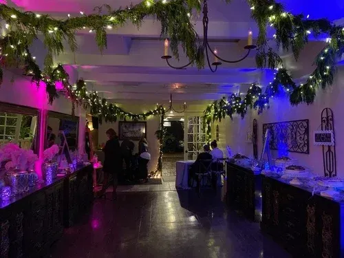 Festive hallway with twinkling lights, garlands, and decorated tables in a dimly lit indoor venue