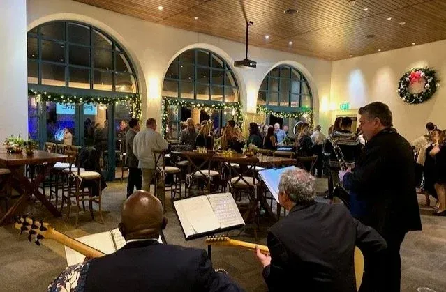 Live jazz band performing in a warmly lit restaurant with diners seated at tables.