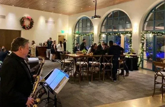 Live band performs in a warmly lit restaurant with diners seated at tables by large arched windows.