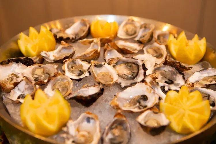 Oyster platter with lemon wedges arranged on ice in a round serving dish