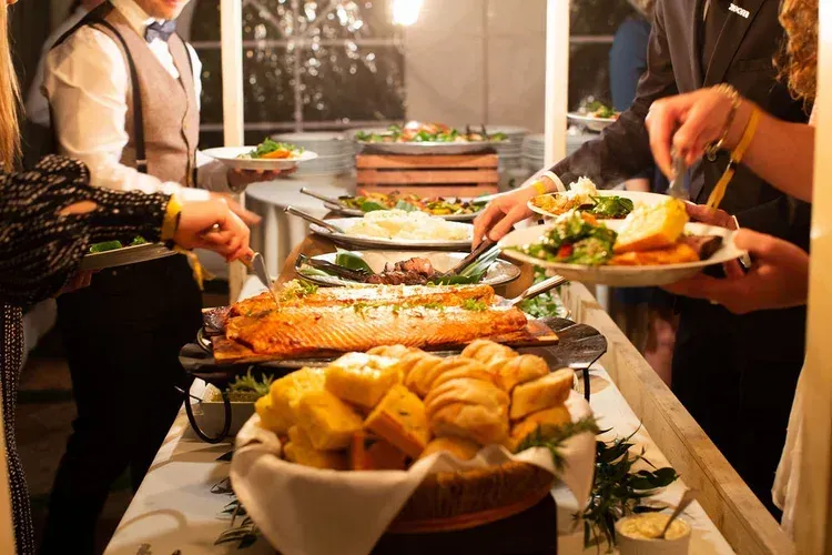Buffet table with assorted dishes as guests serve themselves at an indoor gathering