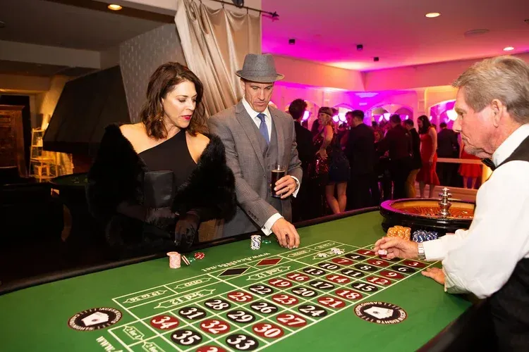 People playing roulette at a casino table under pink and warm lighting