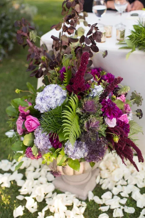 Purple and white floral centerpiece in a beige vase on a table