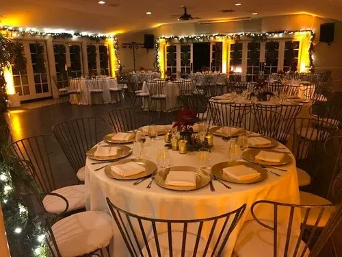 Elegant banquet hall with round tables, white tablecloths, and warm ambient lighting before guests arrive