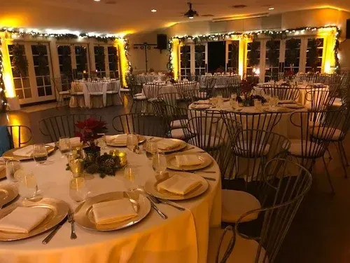Elegant banquet hall with round tables set for a formal dinner, warm lighting, and wire-backed chairs