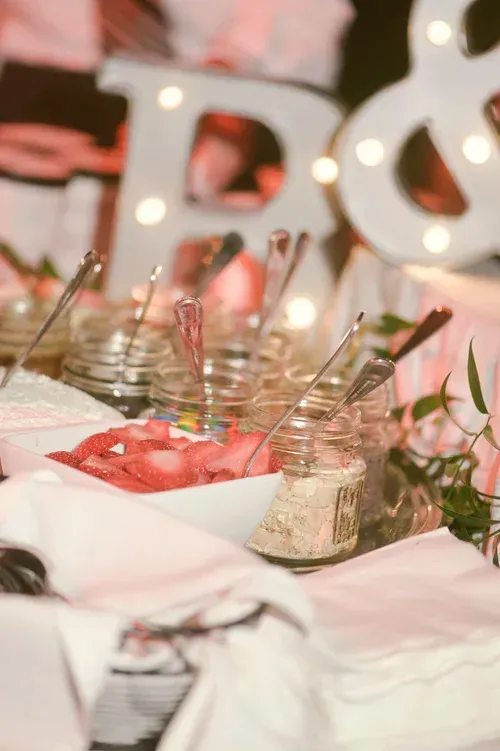 Table setting with white linens, pink floral decor, and glass dessert cups with spoons at an event