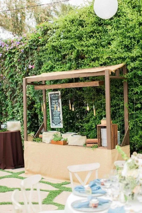 Outdoor wooden wedding arch with greenery, lanterns, and white floral decor in a garden setting