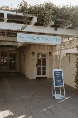 Entrance to Rincon Beach Club with blue sign and a sandwich board on the walkway