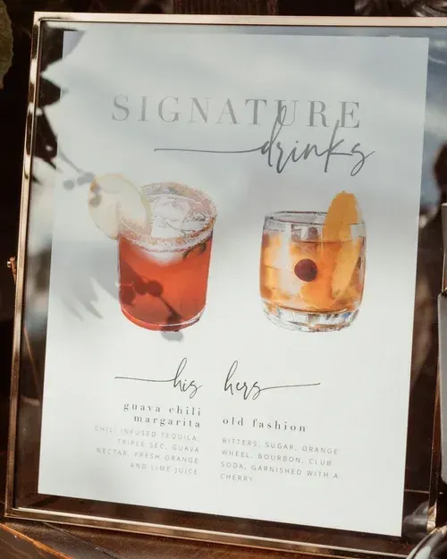 Menu sign for signature drinks with two cocktails, one pink and one amber, on a white display