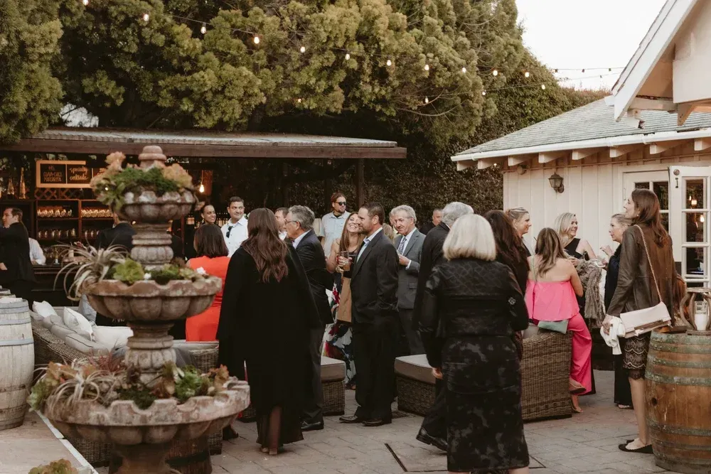Guests mingling at an outdoor market stall with flowers, baskets, and rustic decor