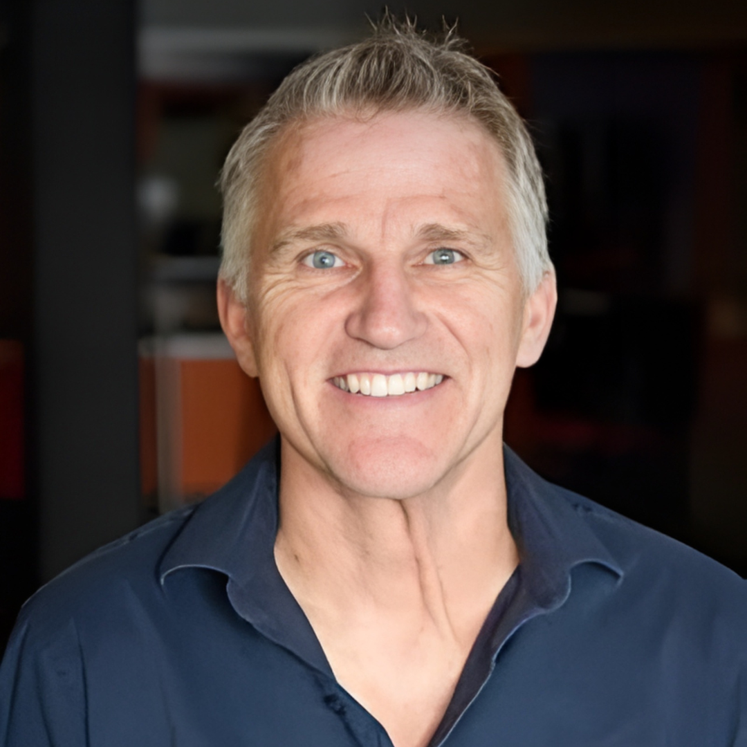 Smiling man in a navy shirt against a blurred dark background