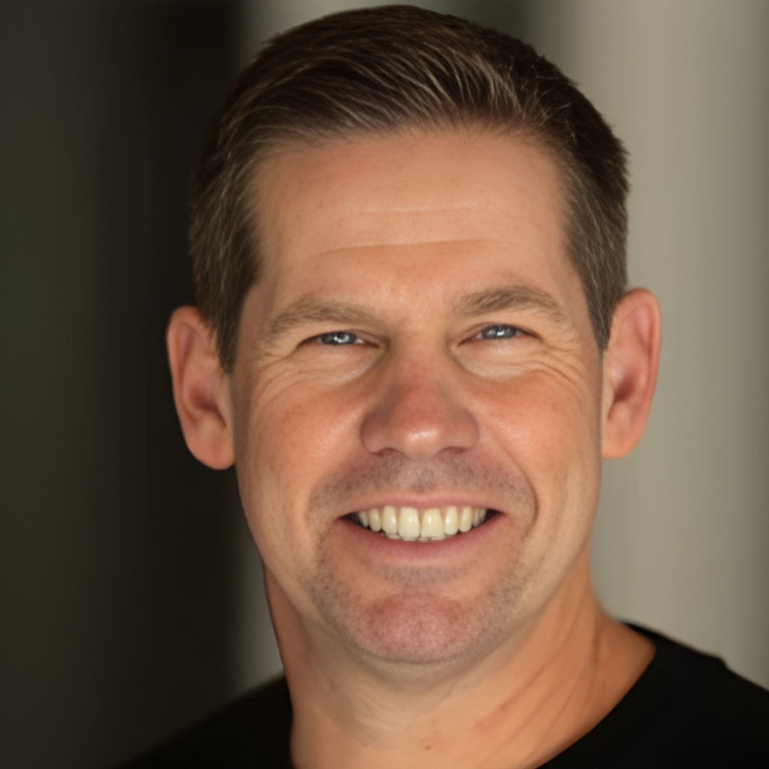 Smiling man in a black shirt against a dark blurred background