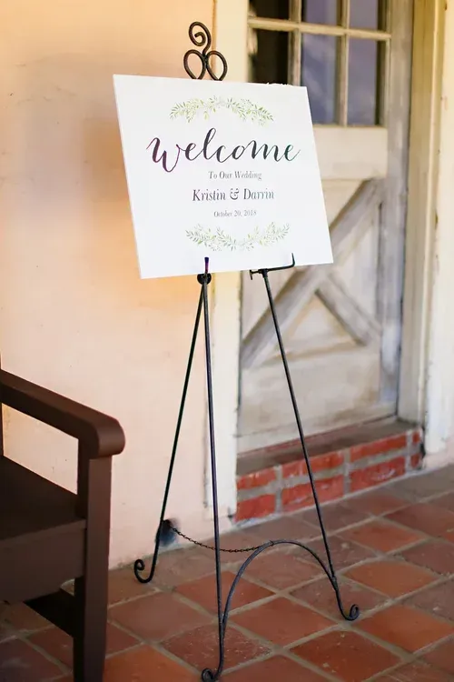 Welcome sign on a black metal easel at a brick entrance.