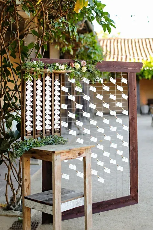 Wooden gate with white diamond cutouts beside a small table in a sunlit courtyard