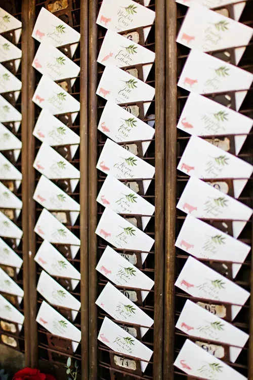 Rows of white paper cards hanging outdoors, each with handwritten notes and small colorful drawings.