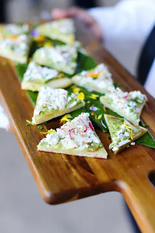 White frosted dessert triangles on a wooden serving board, garnished with green and red sprinkles