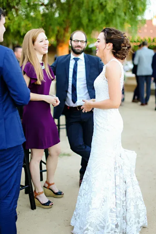 Bride in white dress chatting with guests at an outdoor wedding reception