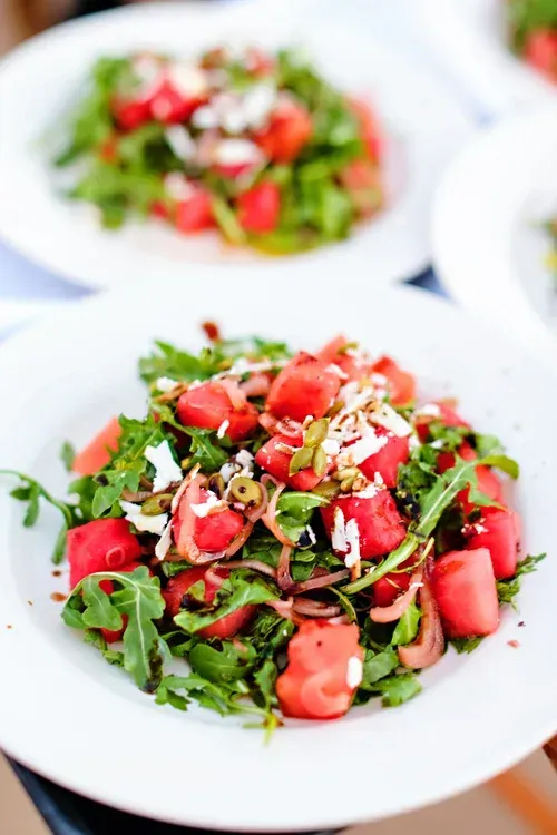 Fresh green salad with tomatoes and herbs served on a white plate