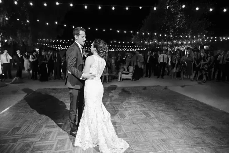 Bride and groom dancing under string lights at an outdoor reception