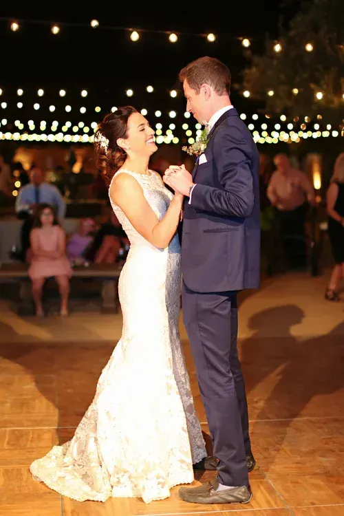 Bride and groom slow dancing on a lit outdoor dance floor at night